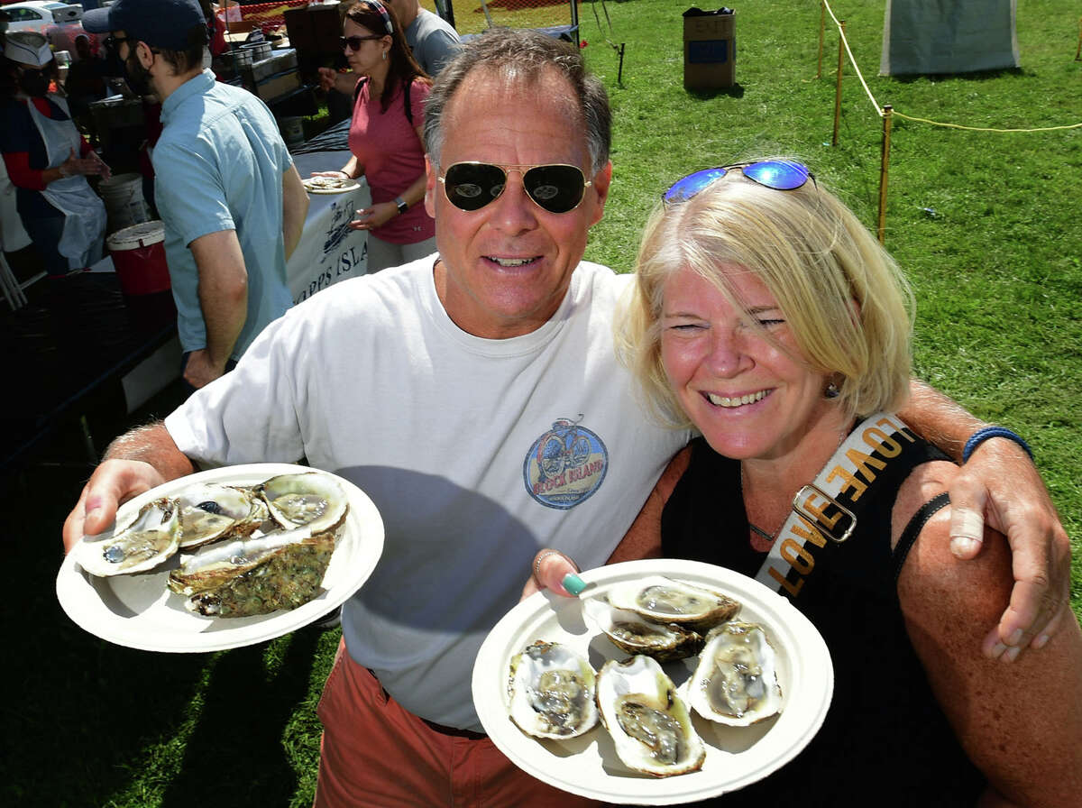 Doug Garaofalo of Stamford and Mary Beth Montague of Greenwich enjoy oysters from the Coast Guard Auxiliary booth during the 43rd Annual Norwalk Oyster Festival Saturday, September 11, 2021, at Veterans Memorial Park in Norwalk, Conn.