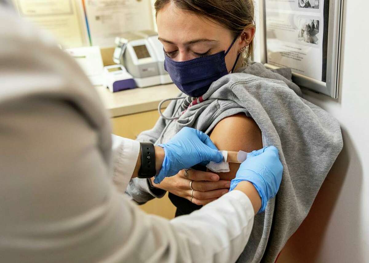 Elizabeth Worthington, 20, of San Francisco watches as nurse practitioner Diana Huang places a bandage over her arm after giving her a flu vaccination at a CVS clinic in San Francisco.