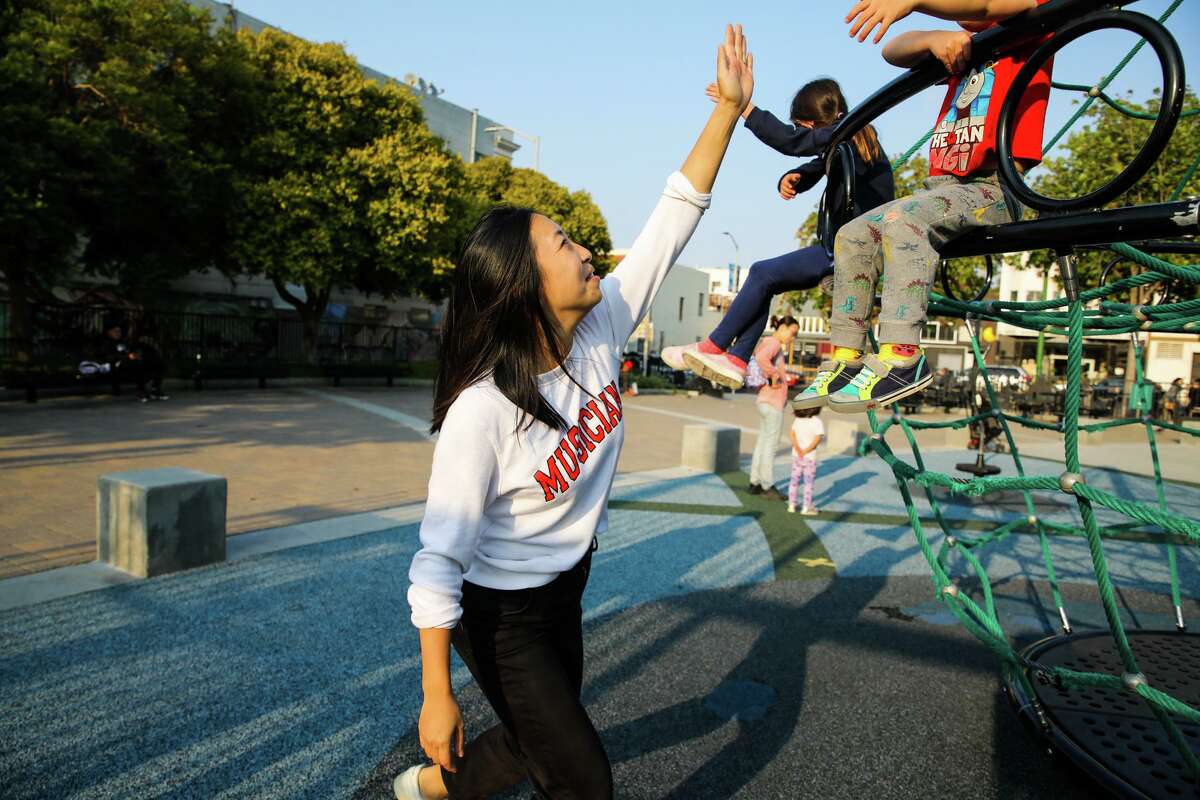 Dumpling Club owner Cathay Bi plays with her children at a playground in San Francisco. She's structured her business to keep boundaries around her personal life, especially so she can be present for her children.
