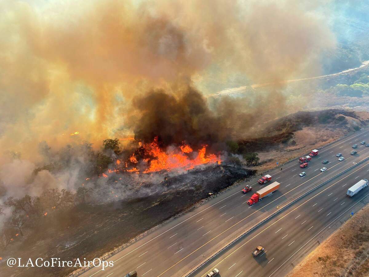 In this aerial photo released by the Los Angeles County Fire Department Air Operations traffic passes the Route fire, a brush wildfire off Interstate 5 north of Castaic, Calif., on Saturday, Sept. 11, 2021. (Los Angeles County Fire Air Operations via AP)