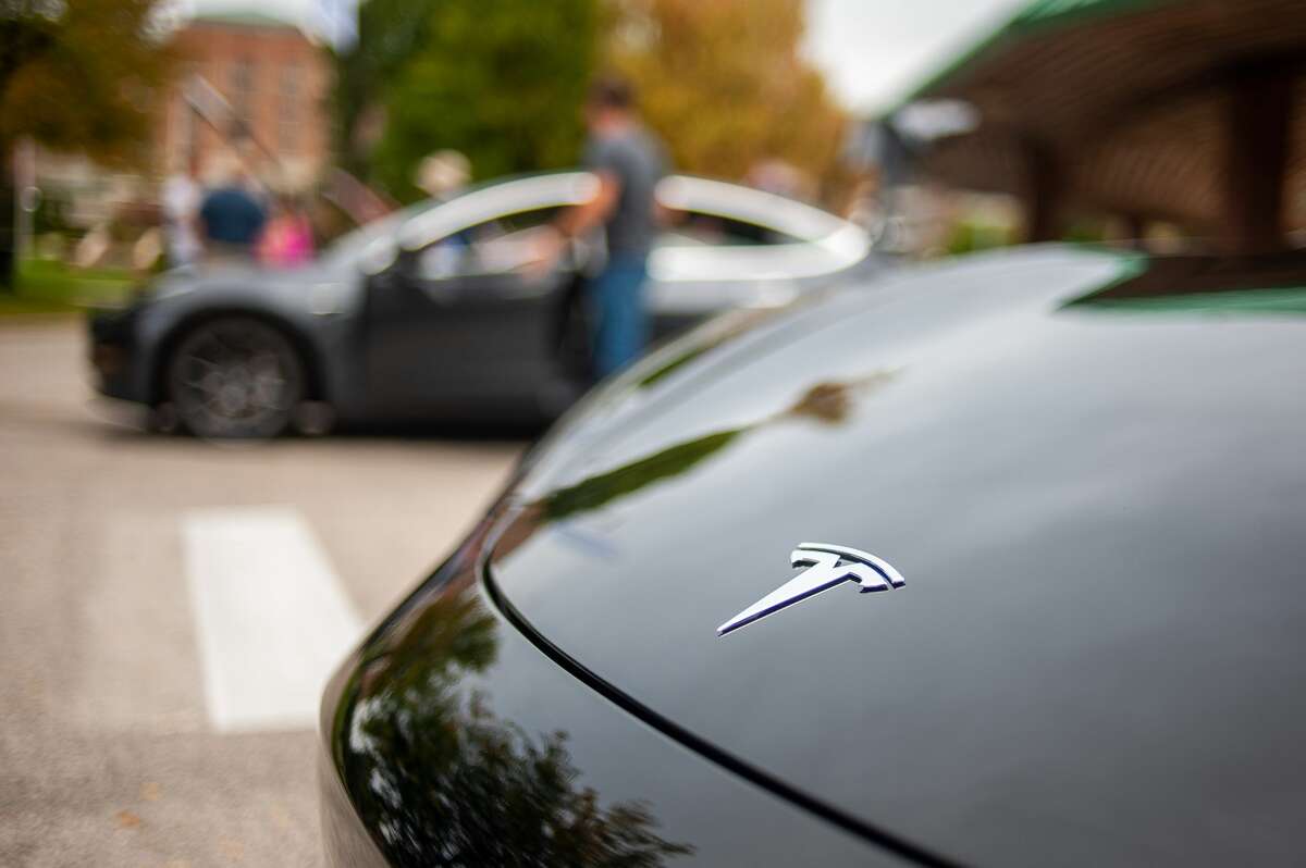 People gather and talk around electric vehicles for the Great Lakes Bay Electric Vehicle Meet Up on Sept. 12, 2021 in the Farmers Market area by the Tridge in Midland. The event also brought Tesla representatives. (Andrew Mullin/AMullin@hearstnp.com)