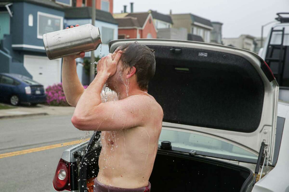 Peterson Harter washes his face after surfing at Ocean Beach in San Francisco. He recently closed his sandwich pop-up for a break to take care of his mental health, and finds relief in surfing.