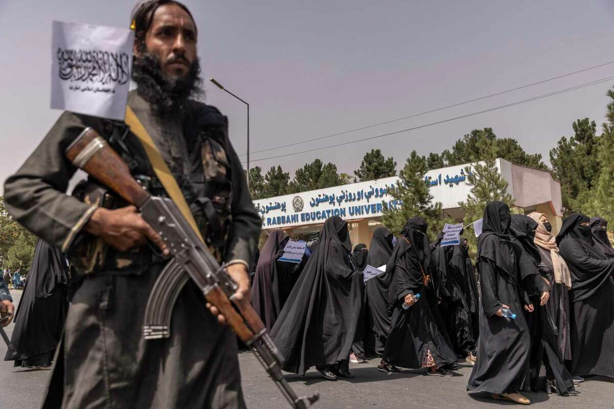 How could 2,500 troops — as President Biden was reportedly advised to keep in Afghanistan — have kept the Taliban at bay in Afghanistan? Here, a Taliban soldier stands guard as women march in support of the new regime in September.