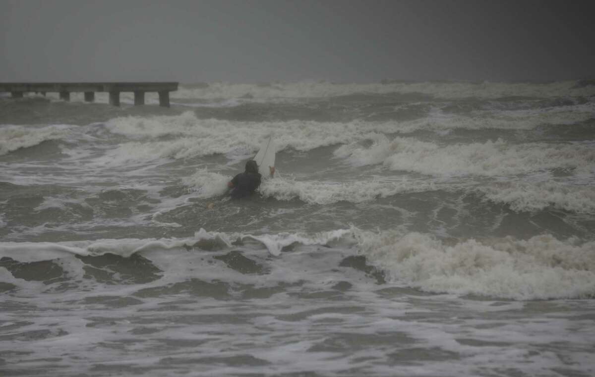 A surfer tries to paddle through the surf as wind and rain from Tropical Storm Nicholas batters the area Monday, Sept. 13, 2021, along the seawall in Galveston.