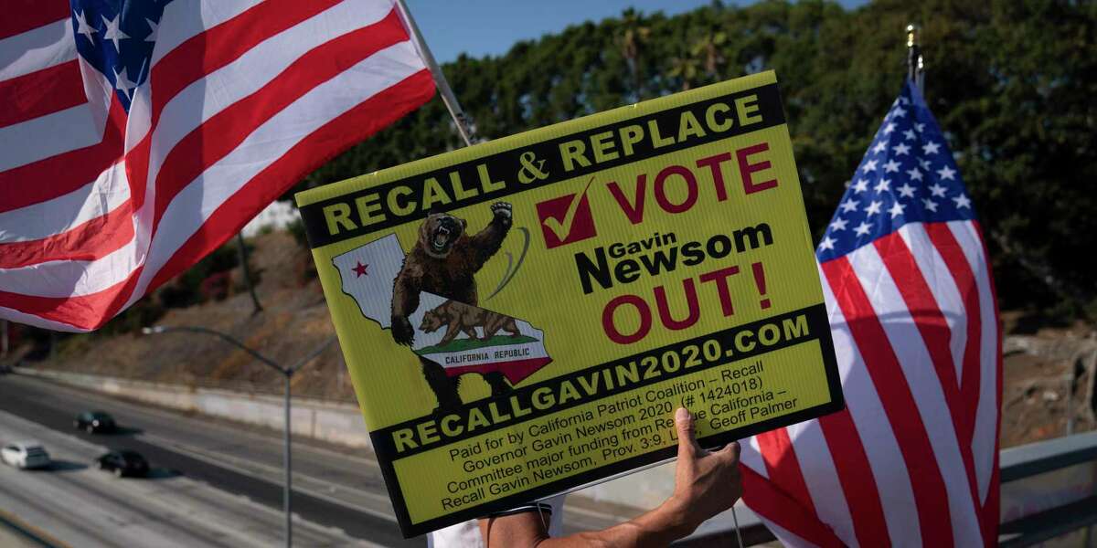 Zig Jiang, 47, carries a sign Sept. 8, urging voters to recall California Gov. Gavin Newsom on a bridge overlooking the 101 Freeway in Los Angeles.