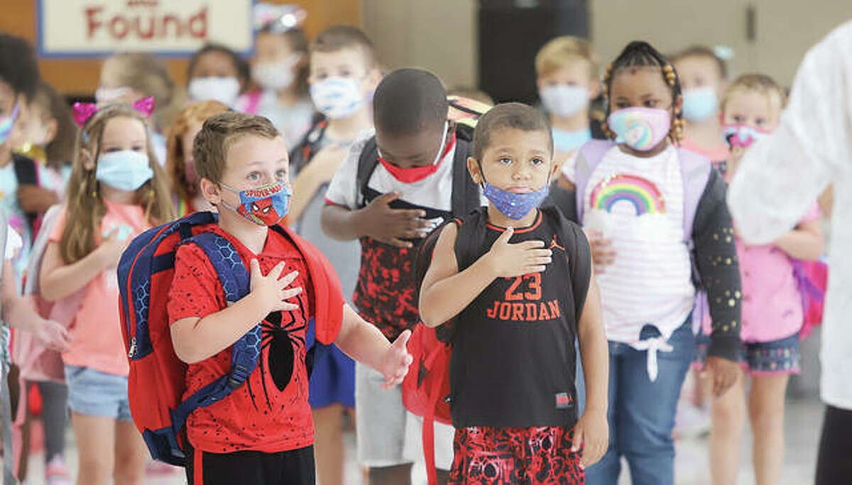 Students at Gilson Brown Elementary School in Godfrey place their hands over their hearts on Aug. 19, the first day of school this year in the Alton School District. On Tuesday legislative oversight panel said it wants the Illinois State Board of Education to adopt formal rules on how it will enforce its indoor mask mandate.