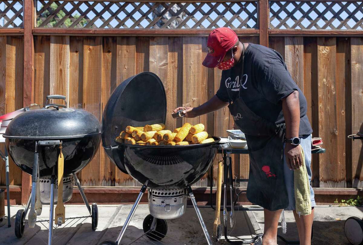 Lee Thomas, founder of GrilleeQ, seasons sweet yellow corn on one of his backyard grills. His home restaurant is the first of its kind to receive a permit from Alameda County’s health department.