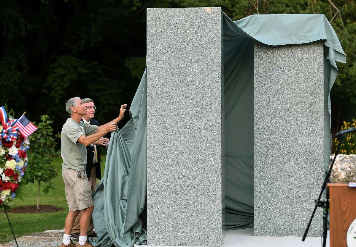 David Powers, left, and Oak Lawn Cemetary Chairman Bronson Hawley unveil the new 9/11 memorial, designed by Powers' brother Dean Powers, at the cemetary in Fairfield, Conn. on Tuesday, September 14, 2021.