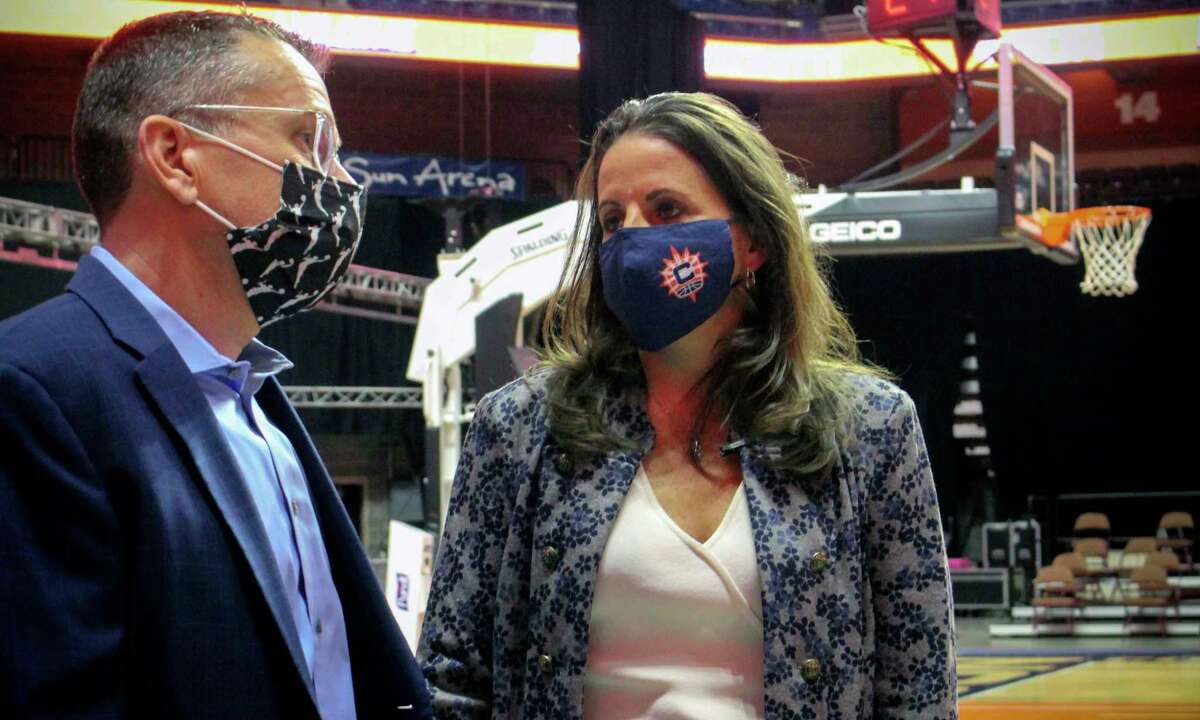 Jennifer Rizzotti, right, speaks with Connecticut Sun head coach Curt Miller, right, following her formal introduction as the new president of the WNBA's Connecticut Sun, Tuesday, April 27, 2021 at the Mohegan Sun Arena in Uncasville, Conn. Rizzotti says she plans to keep her second job this summer as an assistant basketball coach with the United State's women's Olympic basketball team. (AP Photo/Pat Eaton-Robb)