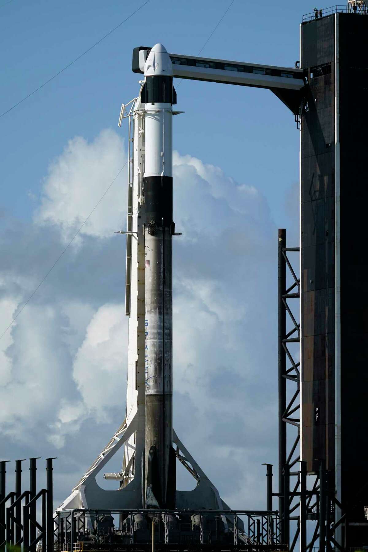 Workers stand on the service structure as a SpaceX Falcon 9 rocket sits on Kennedy Space Center's Launch Pad 39-A in Cape Canaveral, Fla., on Wednesday, Sept. 15, 2021. For the first time in 60 years of human spaceflight, a rocket is poised to blast into orbit with no professional astronauts on board, only four tourists.