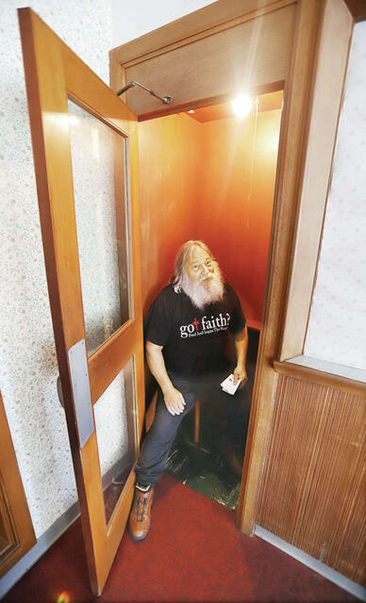 Steve Pegram sits in the built-in phone booth in the corner of lobby of a building donated last week to his ministry. Pegram said people remember the phone booth and ask him if it’s still there; it is, but the phone is gone.