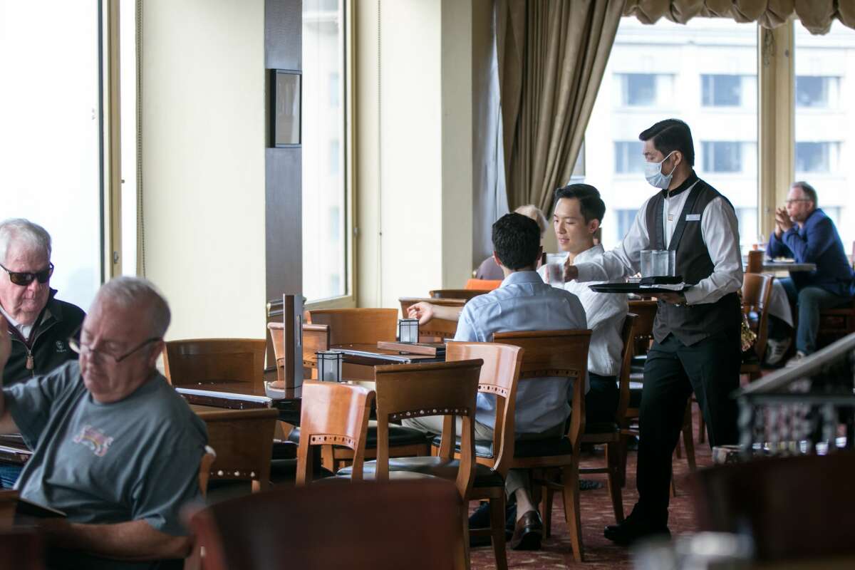 Waiter Frank Mach serves drinks to guests at the Top of the Mark Restaurant and Bar at the InterContinental Mark Hopkins Hotel in San Francisco, California on September 14, 2021.