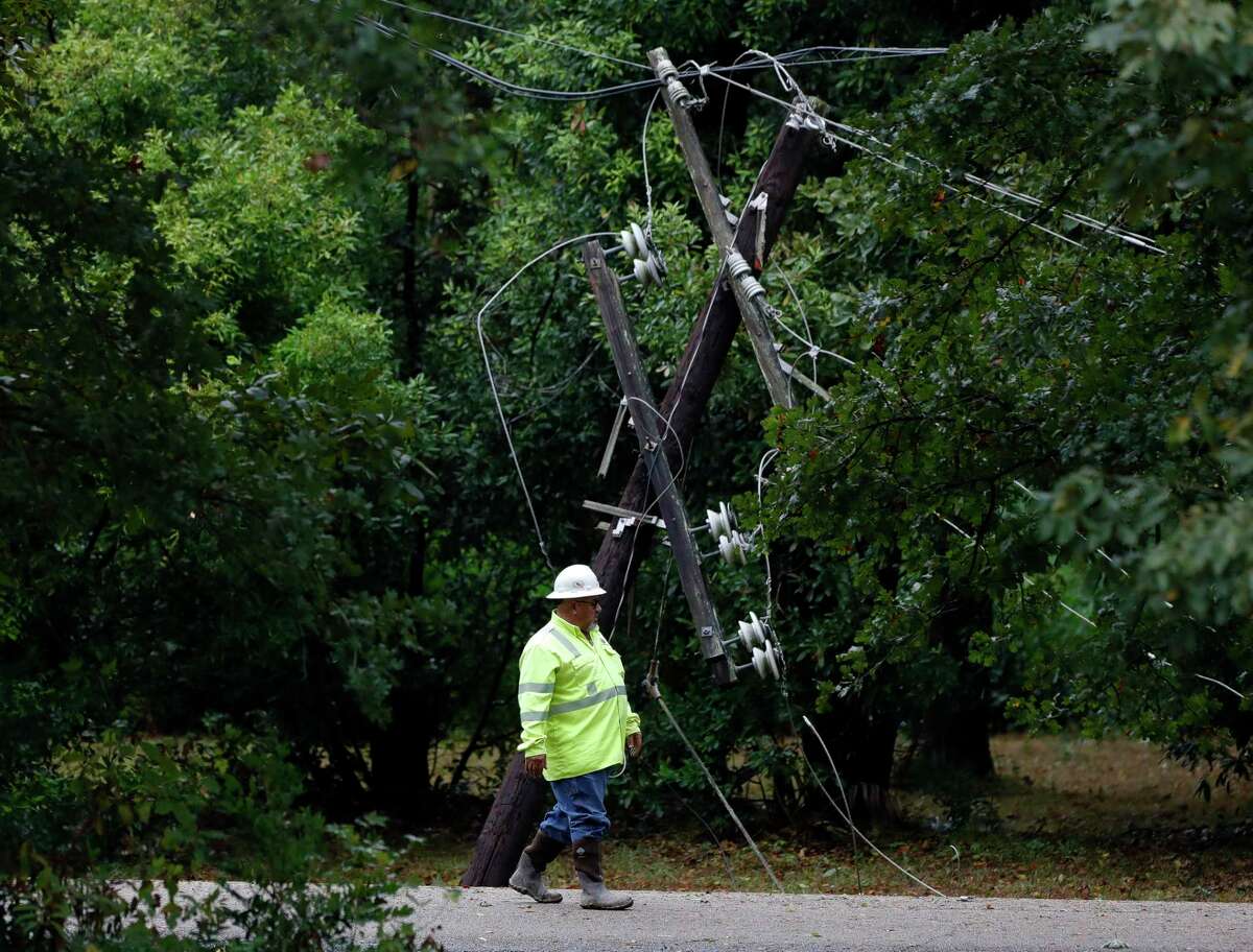 A worker with North Houston Pole Line walks past a downed power line after trees on either side of Braxton Bragg Lane near River Plantation Drive in River Plantation fell overnight as Hurricane Nicholas moved through the region, Tuesday, Sept. 14, 2021, in Conroe.