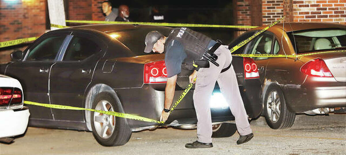 An Alton Police oficer adjusts the crime scene tape around a car early Sept. 9 at the end of the cul-de-sac for Oakwood 700 in the Oakwood Estates housing complex following an incident in which three people were shot.