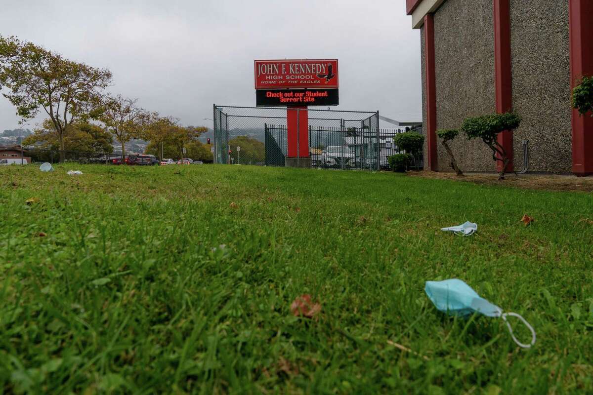A sign board outside of John F. Kennedy High School is seen as discarded masks lay on the school’s lawn in Richmond, Calif., on Tuesday, September 16, 2021.