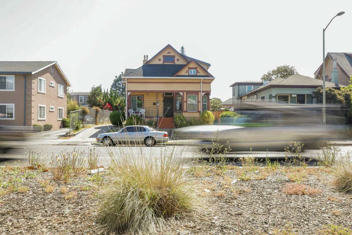 Cars pass by a duplex in Oakland. SB9, which Gov. Gavin Newsom signed Thursday, would make it easier to split lots and convert homes into duplexes.