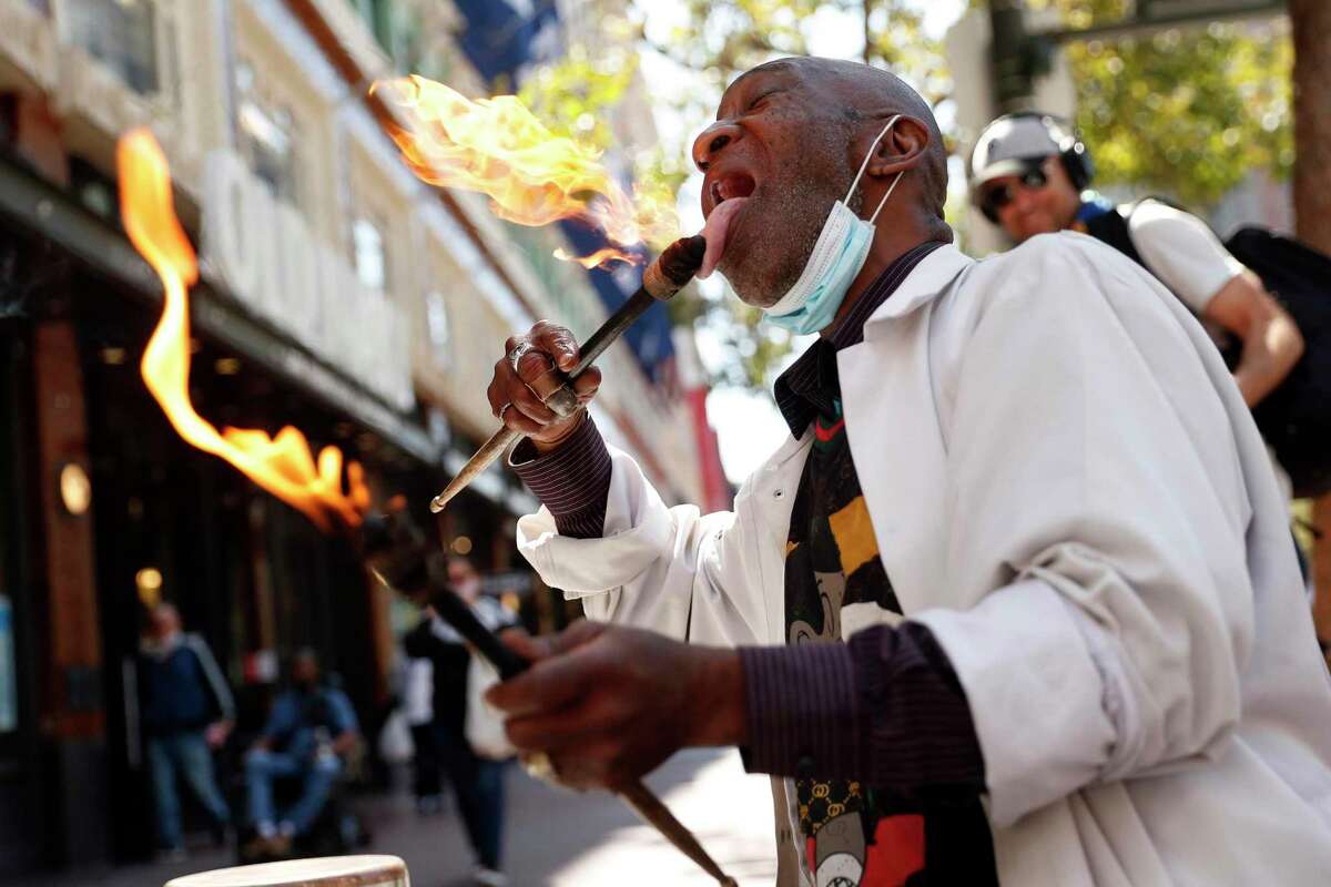 Larry Hunt, the San Francisco Bucket Man, plays his music with flaming drumsticks on Market Street.