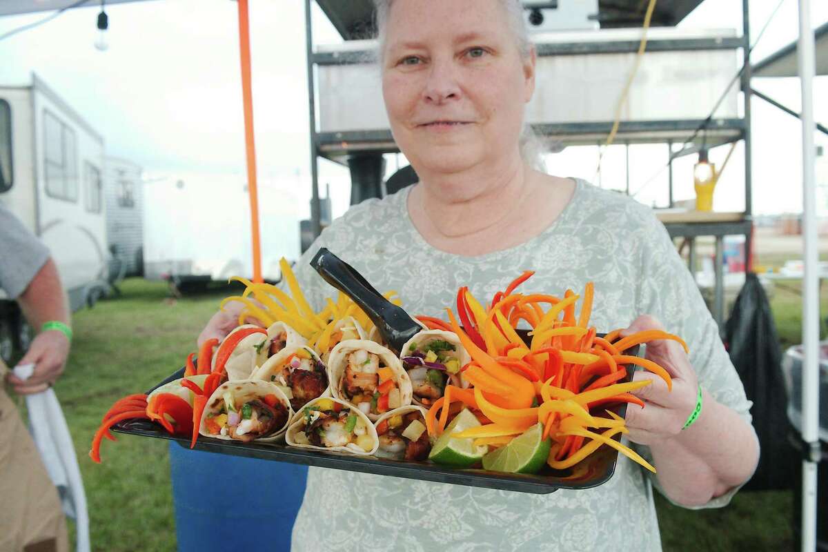 Beth Robinson of Keeping Southern Kookers carries one of her family's signature dishes, fiesta shrimp tacos, out for judging in the cook's choice competition during the Pasadena Livestock Show and Rodeo.