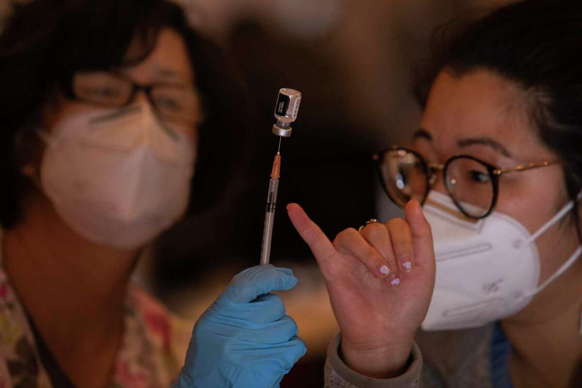 Rosa Cheng (left), a clinical registered nurse lead with Visit Healthcare, and physician assistant Chelsea Liu draw a Pfizer vaccine into a syringe at a new vaccination site at Balboa High School in San Francisco on Wednesday.