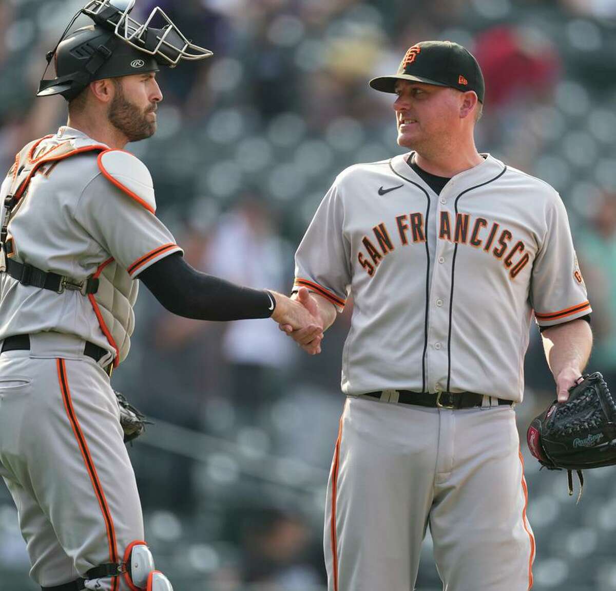San Francisco Giants catcher Curt Casali, left, congratulates relief pitcher Jake McGee after the team's baseball game against the Colorado Rockies on Wednesday, Sept. 8, 2021, in Denver. The Giants won 7-4. (AP Photo/David Zalubowski)