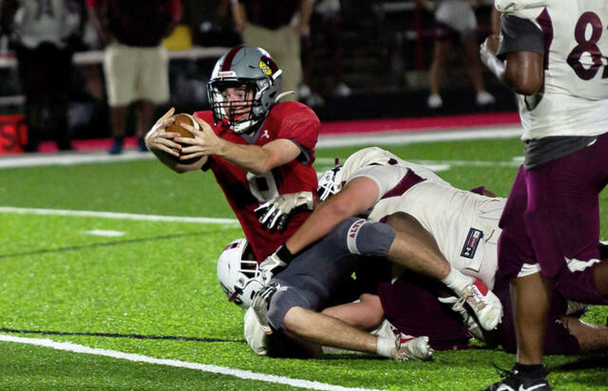Redbirds quarterback Graham McAfoos (9) stretches for an extra yard late in the fourth quarter in Alton’s 6-3 victory over Belleville West Friday night.