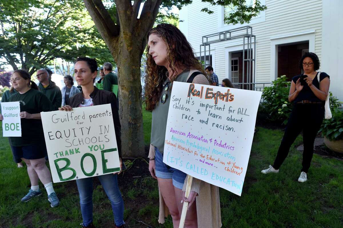 Christine Saari, left, and Lauren Dennehy, center, of Guilford, protest before a forum on critical race theory at the Nathanael B. Greene Community Center in Guilford on June 24, 2021.
