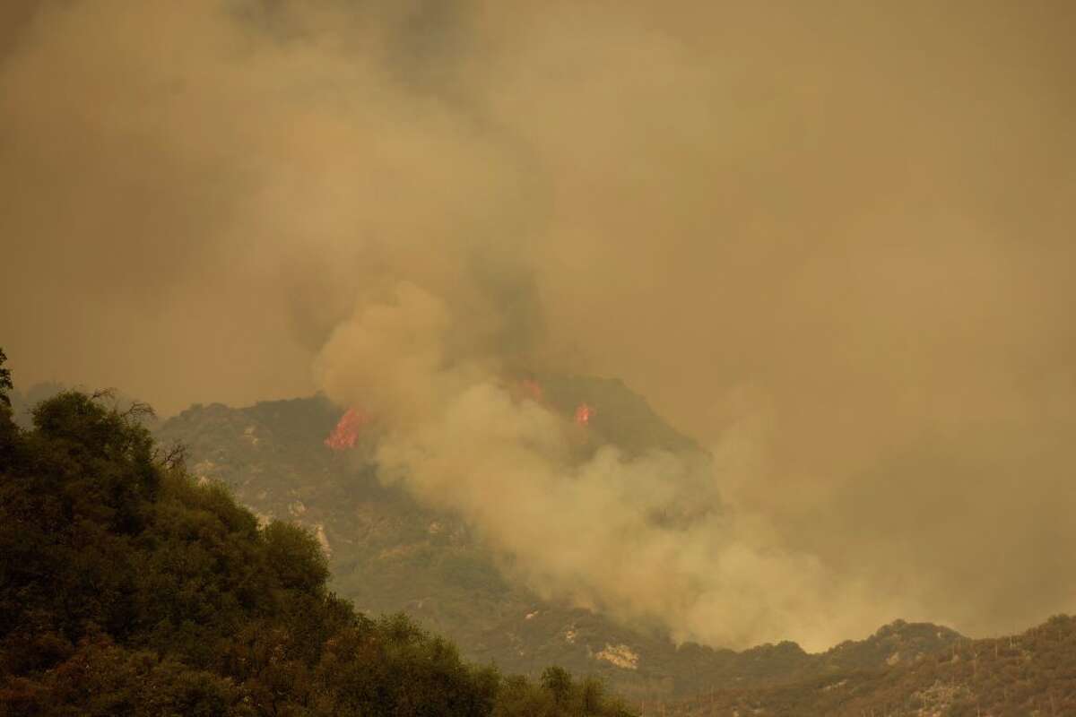 A plume of smoke and flames rise in the air as fire burns towards Moro Rock during the KNP Complex fire in Sequoia National Park near Three Rivers, Calif., September 18, 2021. 