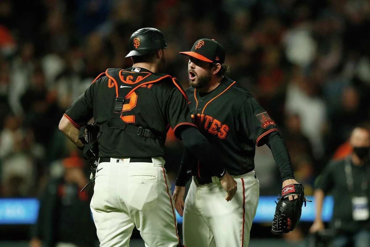 SAN FRANCISCO, CALIFORNIA - SEPTEMBER 18: Catcher Curt Casali #2 and closing pitcher Dominic Leone #52 of the San Francisco Giants celebrate after a win against the Atlanta Braves at Oracle Park on September 18, 2021 in San Francisco, California. (Photo by Lachlan Cunningham/Getty Images)