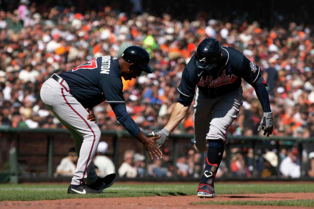 Atlanta’s Adam Duvall (right) gets a low-five from third-base coach Ron Washington after hitting a two-run home run off San Francisco Giants starting pitcher Anthony DeSclafani during the seventh inning.