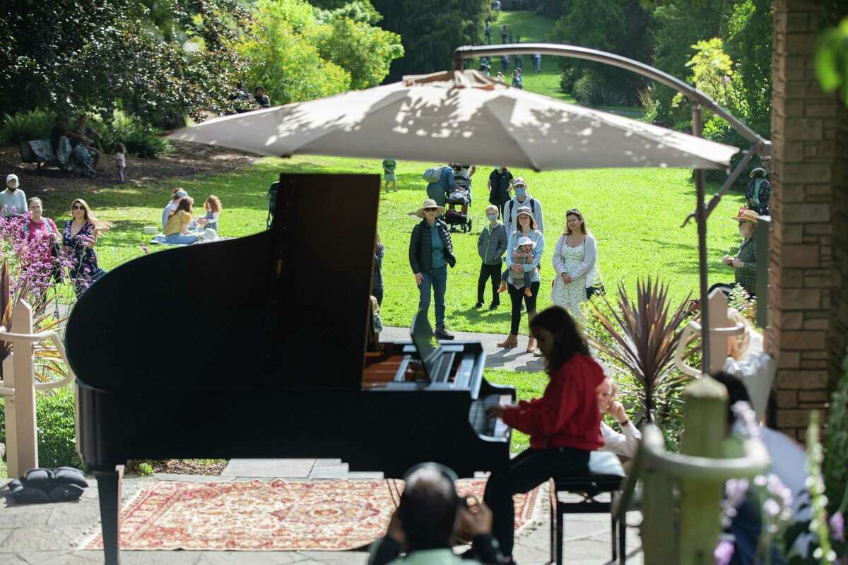 Onlookers in the San Francisco Botanical Gardens in Golden Gate Park enjoy the music of a young pianist during the Flower Piano event.