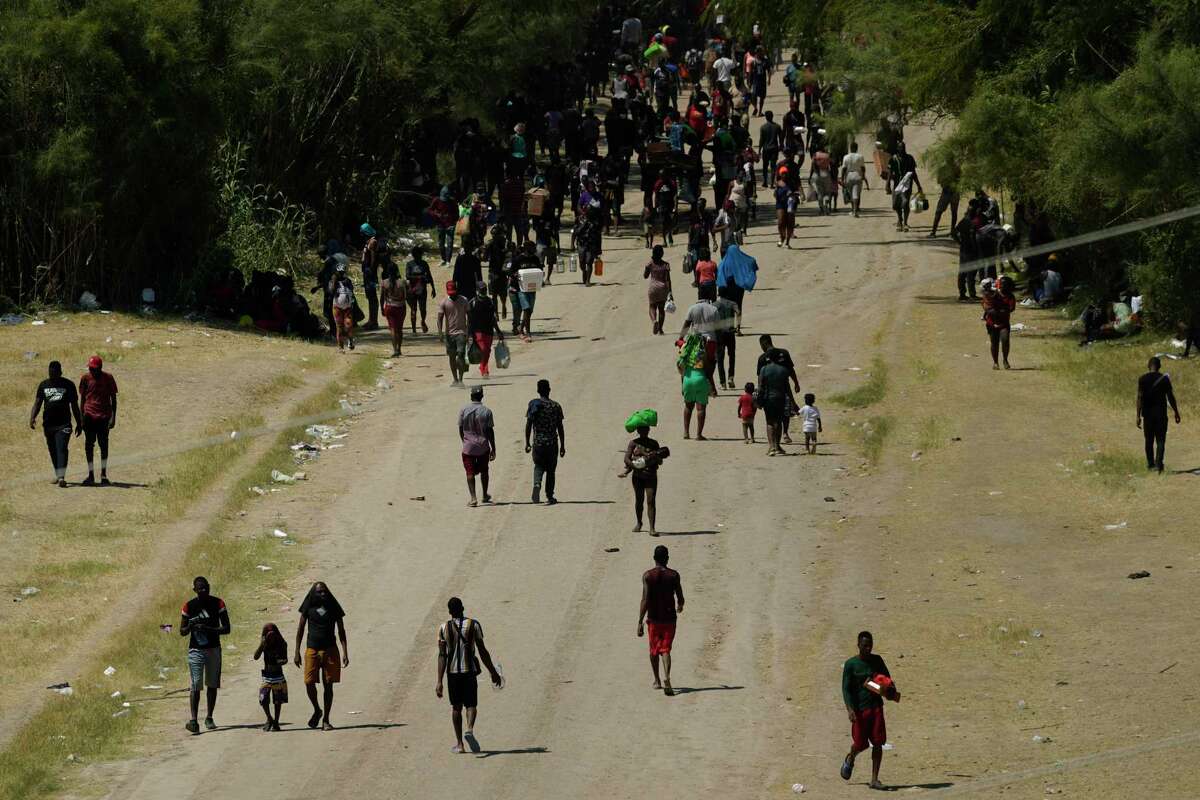 Migrantes haitianos caminan por un camino de tierra después de ingresar a Estados Unidos desde México, el viernes 17 de septiembre de 2021, en Del Rio, Texas.