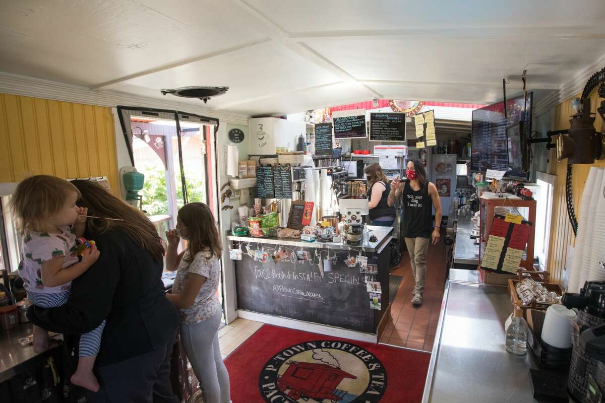 P-Town Coffee and Tea owners, center back, Ashlee Shelton and Jeremy-Tristahn Bascara Jr. help out customers inside their cafe in a train caboose in Pacifica, Calif., on Sept. 15 ,2021.