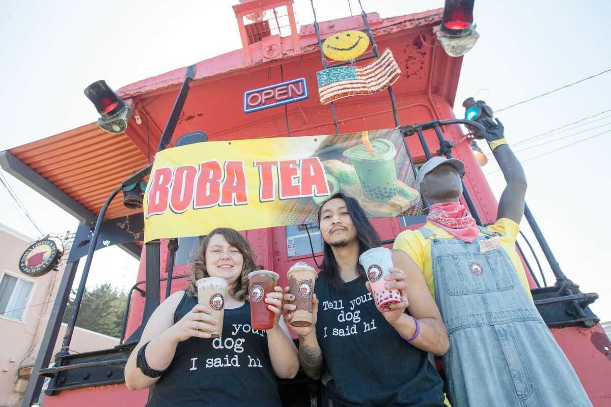 P-Town Coffee and Tea owners Ashlee Shelton, left, and Jeremy-Tristahn Bascara Jr. hold some of their signature boba offerings outside their cafe, located in a train caboose, in Pacifica, Calif.