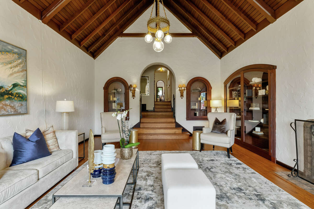 The home was built in 1929 and reverence for the home's original design is obvious. The millwork and oak paneled library, diamond and Vermeer cross leaded glass windows, arched panel castle doors, peaked ceilings embellished with exposed beams, and abundance of rich hardwood are all classic hallmarks of this architecture. The living room offers soaring ceilings paneled in dark wood.
