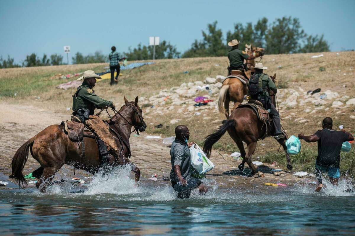 U.S. Customs and Border Protection mounted officers attempt to contain migrants as they cross the Rio Grande from Ciudad Acuña into Del Rio, Texas, Sunday, Sept. 19, 2021. Thousands of Haitian migrants have been arriving to Del Rio, Texas, as authorities attempt to close the border to stop the flow of migrants. (AP Photo/Felix Marquez)