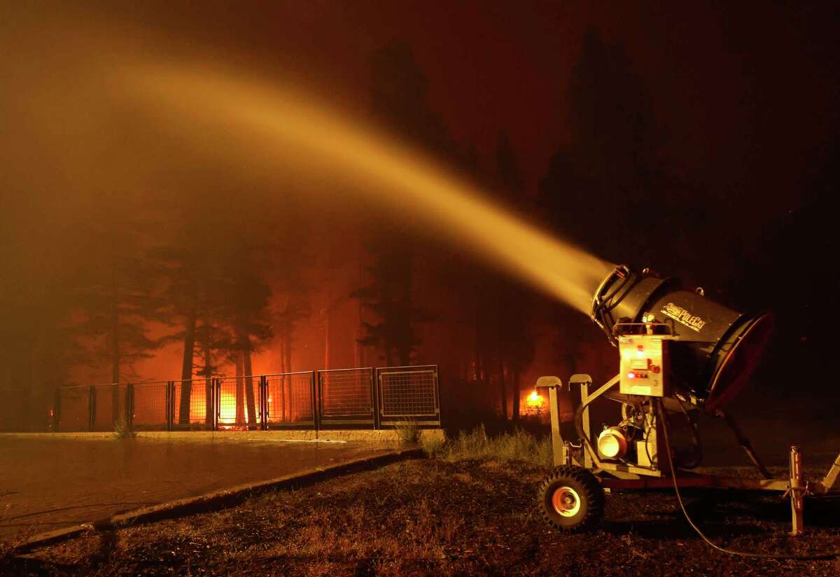 TWIN BRIDGES, CALIFORNIA - AUGUST 30: A snow machine blows water on a structure at Sierra-at Tahoe ski resort as the Caldor Fire moves through the area on August 30, 2021 in Twin Bridges, California. The Caldor Fire has burned over 165,000 acres, destroyed over 650 structures and is currently 13 percent contained. (Photo by Justin Sullivan/Getty Images)
