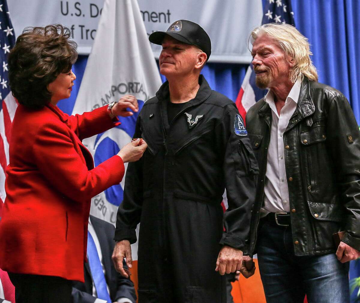 CJ Sturckow, left, receives wings from the FAA's Commercial Space Astronaut Wings program. Sturckow received these wings because he was a pilot on Virgin Galactic's SpaceShipTwo and flew it over 50 miles above the Earth's surface. To her right is Virgin Galactic founder Richard Branson.