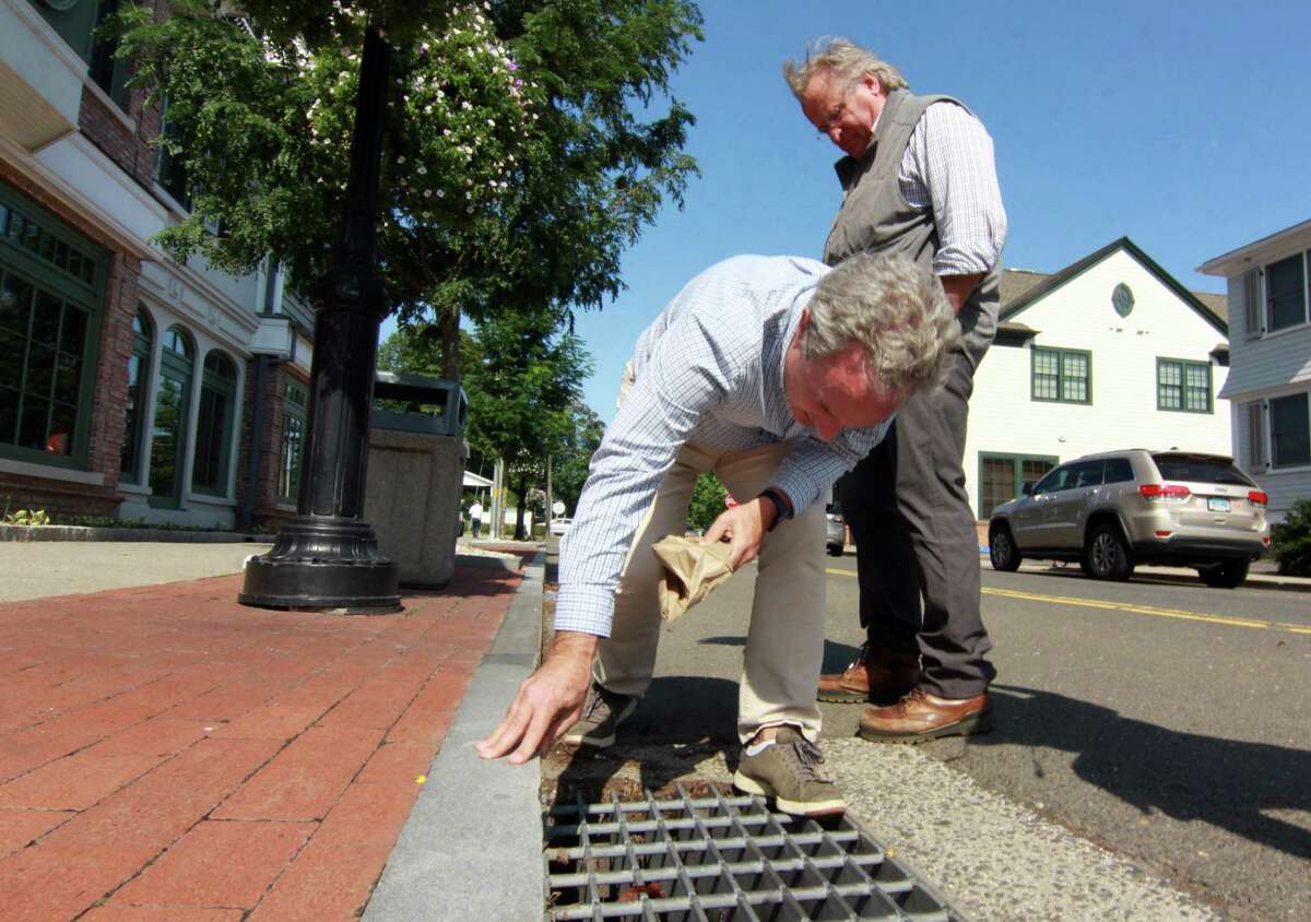 Local business owners Al Tibbetts and David Genovese, standing in back, try to get a look at storm drains that backed up during a tour of businesses damaged by flooding from Hurricane Ida by Governor Ned Lamont and First Selectman Jayme Stevenson in Darien, Conn., on Friday Sentember 10, 2021.