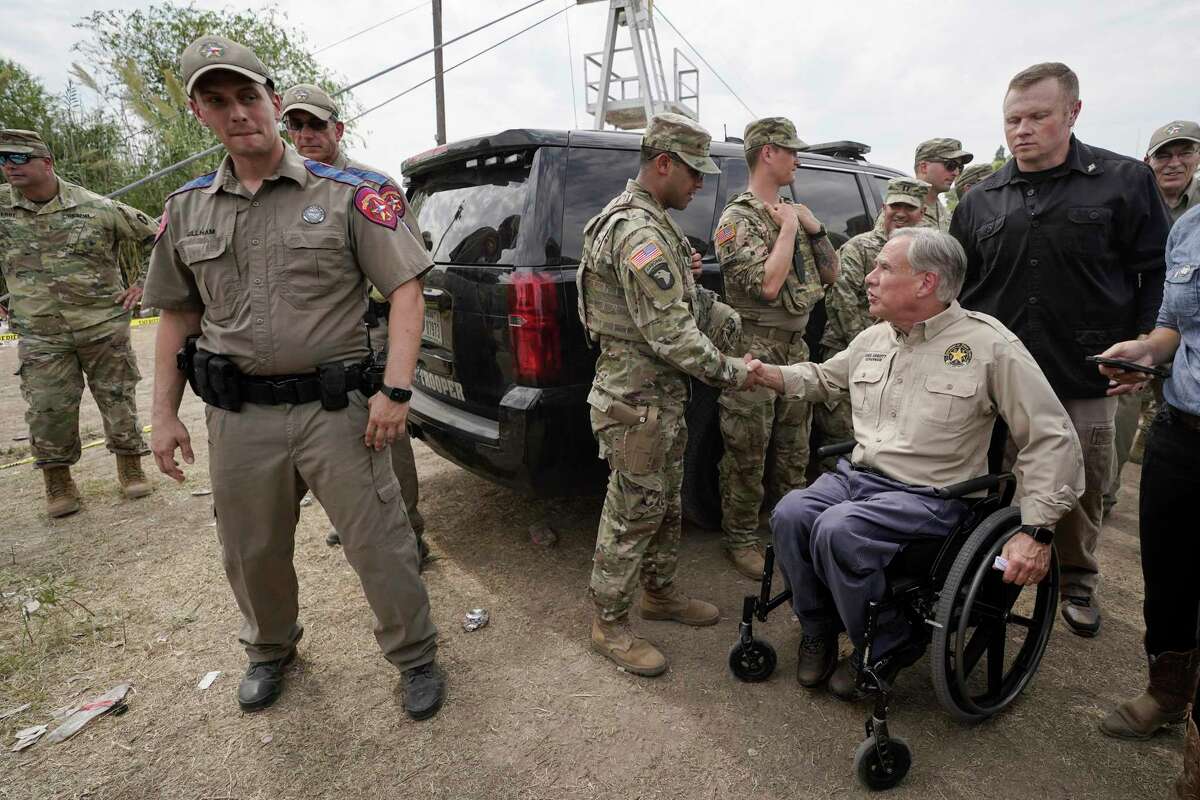 Texas Gov. Greg Abbott, right, shakes a National Guard member's hand after speaking during a news conference along the Rio Grande, Tuesday, Sept. 21, 2021, in Del Rio, Texas. The U.S. is flying Haitians camped in a Texas border town back to their homeland and blocking others from crossing the border from Mexico. (AP Photo/Julio Cortez)