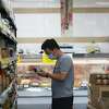2021年8月12日，周四，在加州圣马特奥，一名购物者在Suruki超市购物时从货架上挑选商品。