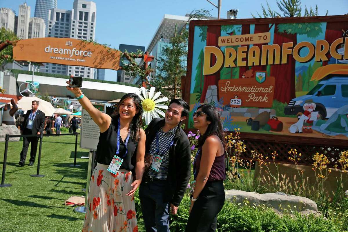 “梦想力量2022”如何影响旧金山市区的交通、公共交通。Salesforce的员工Taksina Eammano(从左到右)、Victor Liu和Nithya Lakshmanan在旧金山莫斯康中心参加Salesforce的“梦想力量2021”会议时在国际公园的入口处合影。