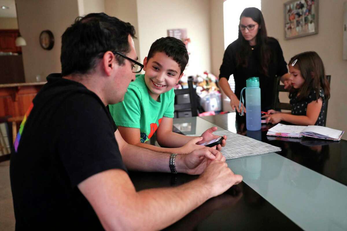Miguel Chavez and his son, Nico, 9, order dinner on an app as his wife, Renee, interacts with their daughter, Sofia, 6, at their home in Castro Valley, Calif., on Monday, September 20th, 2021. The Chavez children were enrolled in a COVID-19 vaccine trial at Stanford.