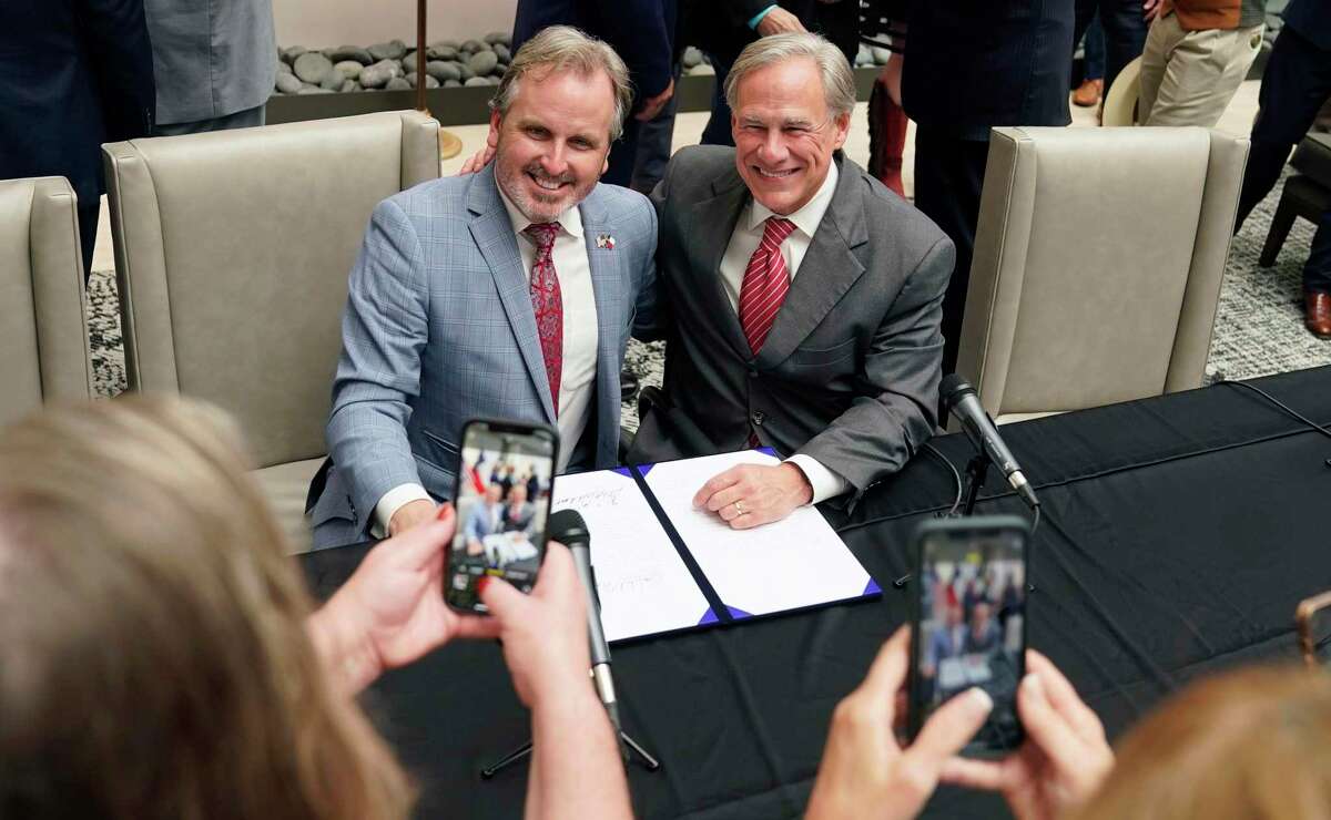 Texas Gov Greg Abbott, right and State Sen. Bryan Hughes, R-Mineola, pose for photos after Abbott signed Senate Bill 1, also known as the election integrity bill, into law in Tyler, Texas, Tuesday, Sept. 7, 2021. The sweeping bill signed by the two-term Republican governor further tightens Texas' strict voting laws. (AP Photo/LM Otero)