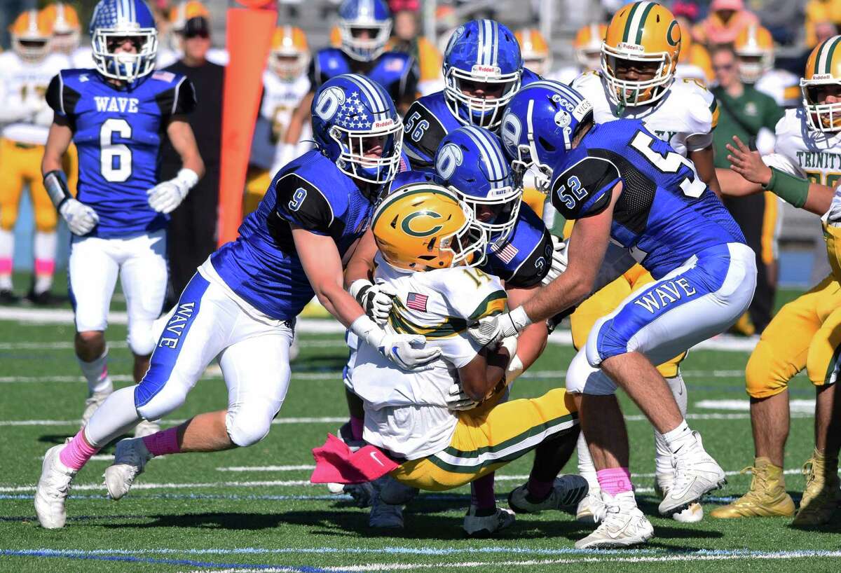 The Darien defense, including Sam Wilson (9), David Evanchick (33) and Will Bothwell (52) tackle Trinity Catholic's Branden Louis (14) during a football game at Darien High School on Saturday, Oct. 19, 2019.