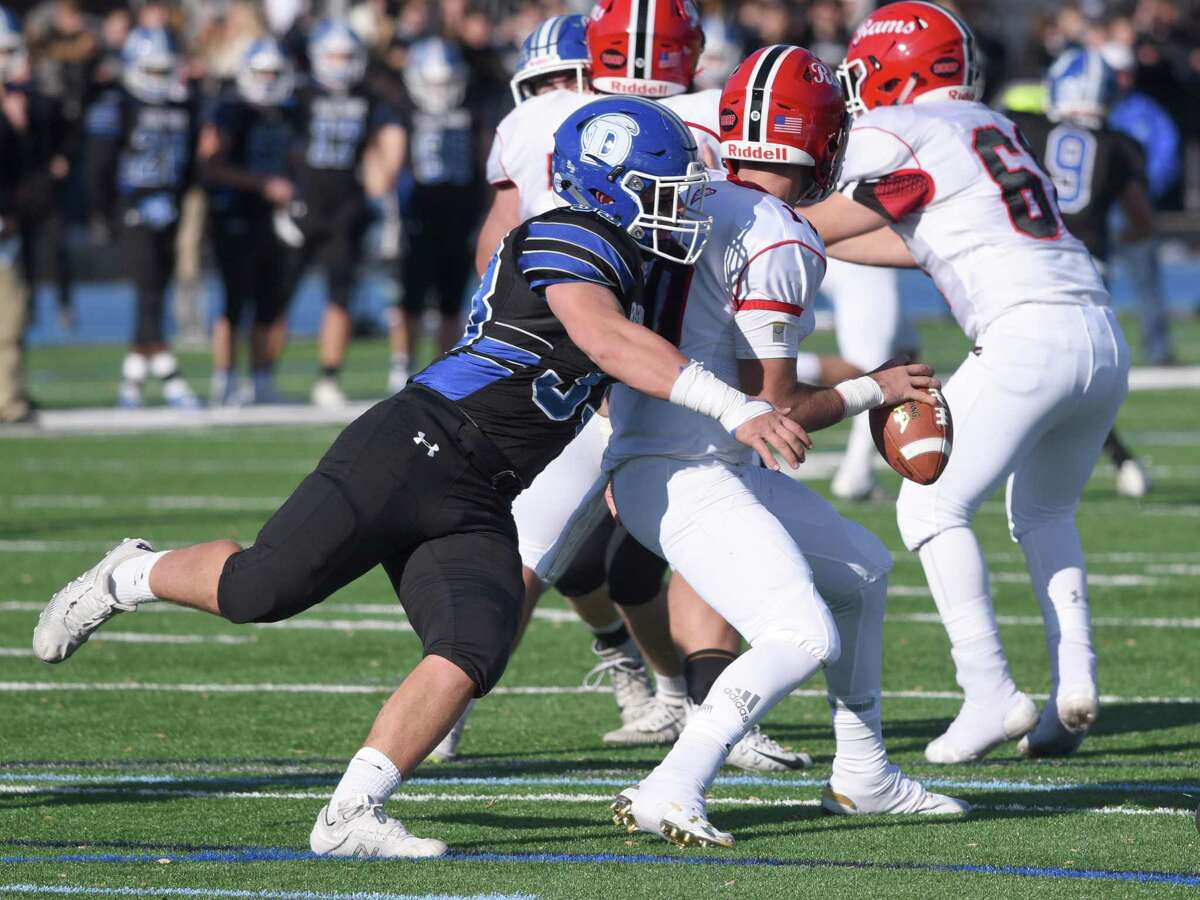 Darien’s David Evanchick (33) tries to bring down New Canaan’s Drew Pyne (10) during the annual Turkey Bowl football game between Darien and New Canaan at Darien High School on Nov. 28, 2019.