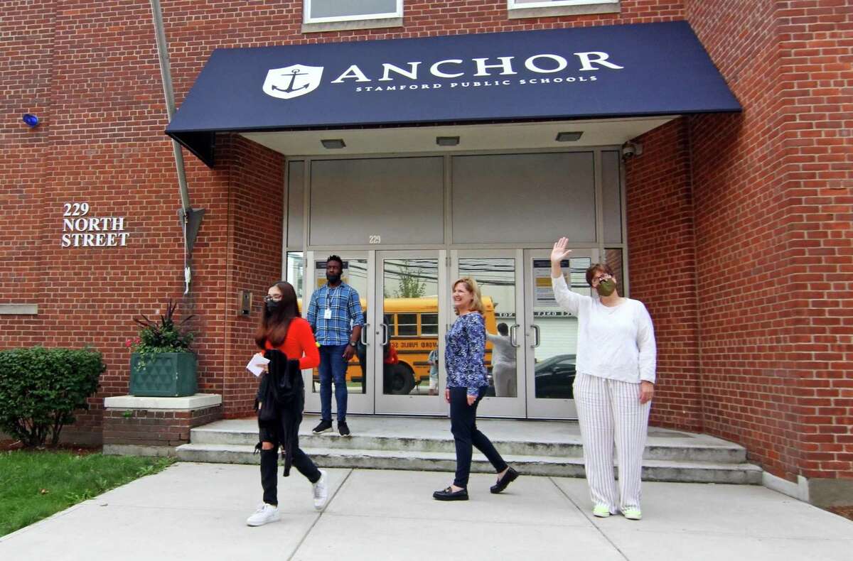 Anchor School Director Laura Greene, in back center, and Jenn Chichester, right, watches as some of their students board the bus in front of the school's new location on North Street in Stamford, Conn., on Wednesday September 22, 2021.