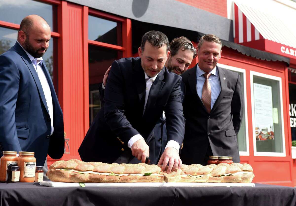 Cardona's Market co-owners Robert, center left, and August Cardona, center right, celebrate the opening of their new store in the former Roma Foods location with the cutting of a giant sandwich on Thursday, September 23 2021, on Cobbee Road in Colonie, NY