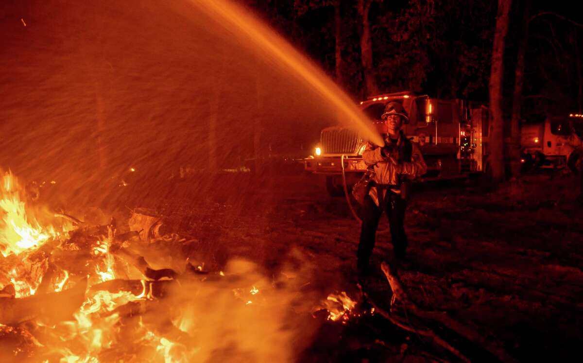 Firefighter Ron Burias battles the Fawn Fire as it spreads north of Redding on Thursday.