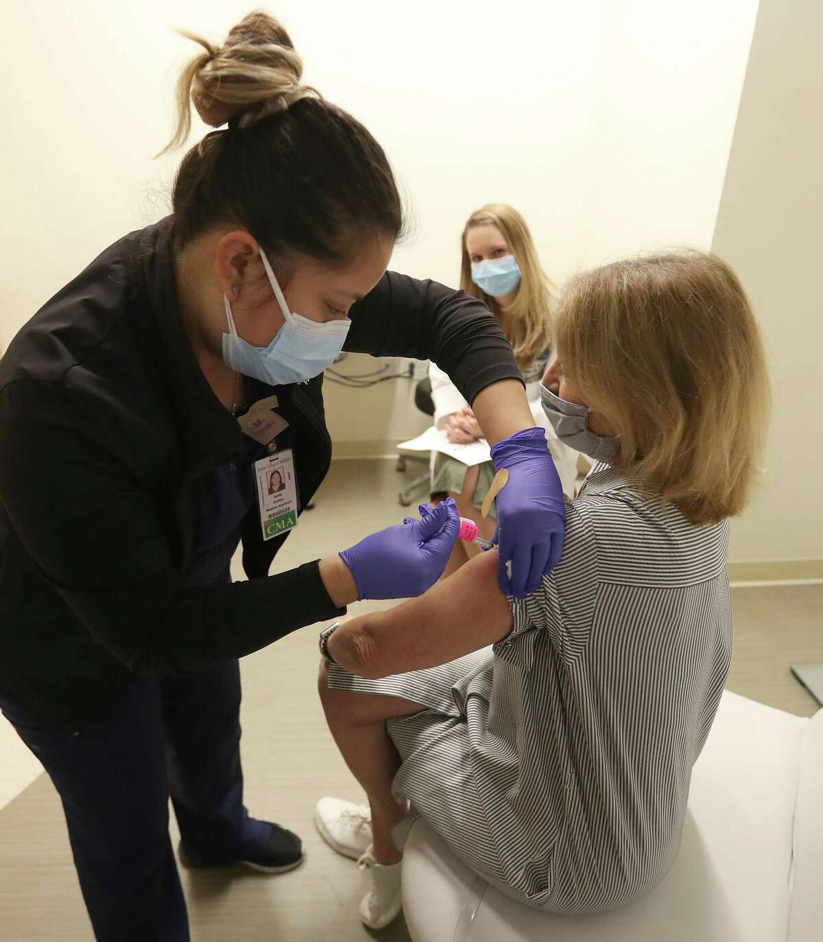 Anita Cortez, CMA, gives RN Liz Bernica her third dose of the Pfizer vaccine, as a booster, while her daughter-in-law, Dr. Jessica Bernica watched at Baylor College of Medicine, Friday, September 24, 2021, in Houston, after the CDC gave boosters the go ahead last night.