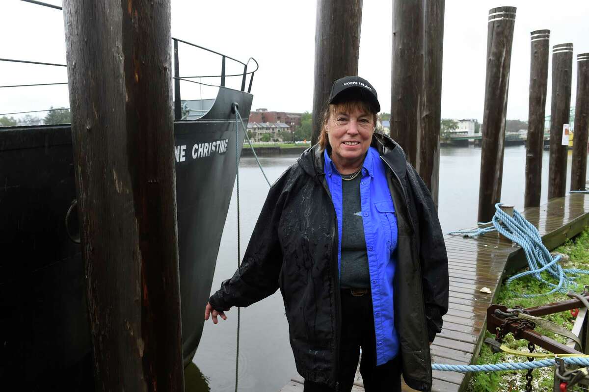 Patty King, Booth Manager at Copps Island Oysters Farm, is pictured by oyster dredging boat Jeanne Christine on Quinnipiac Avenue in New Haven on September 24, 2021.